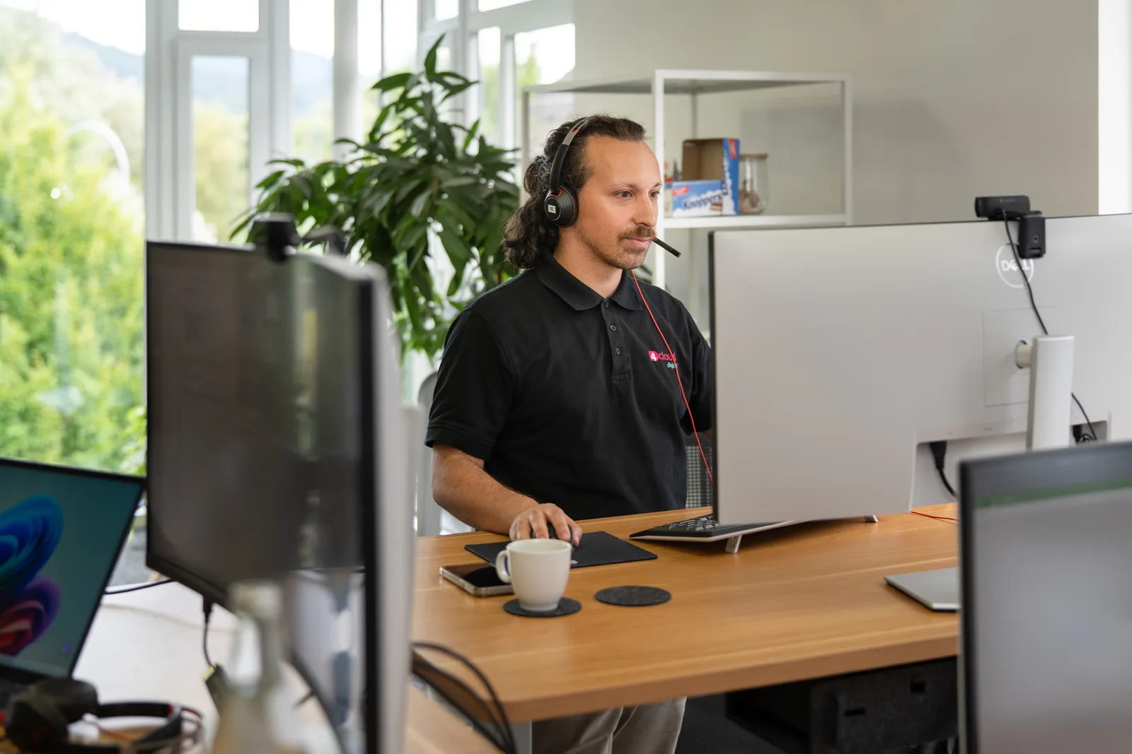 Kollege mit Headset bearbeitet eine Anfrage am Bildschirm